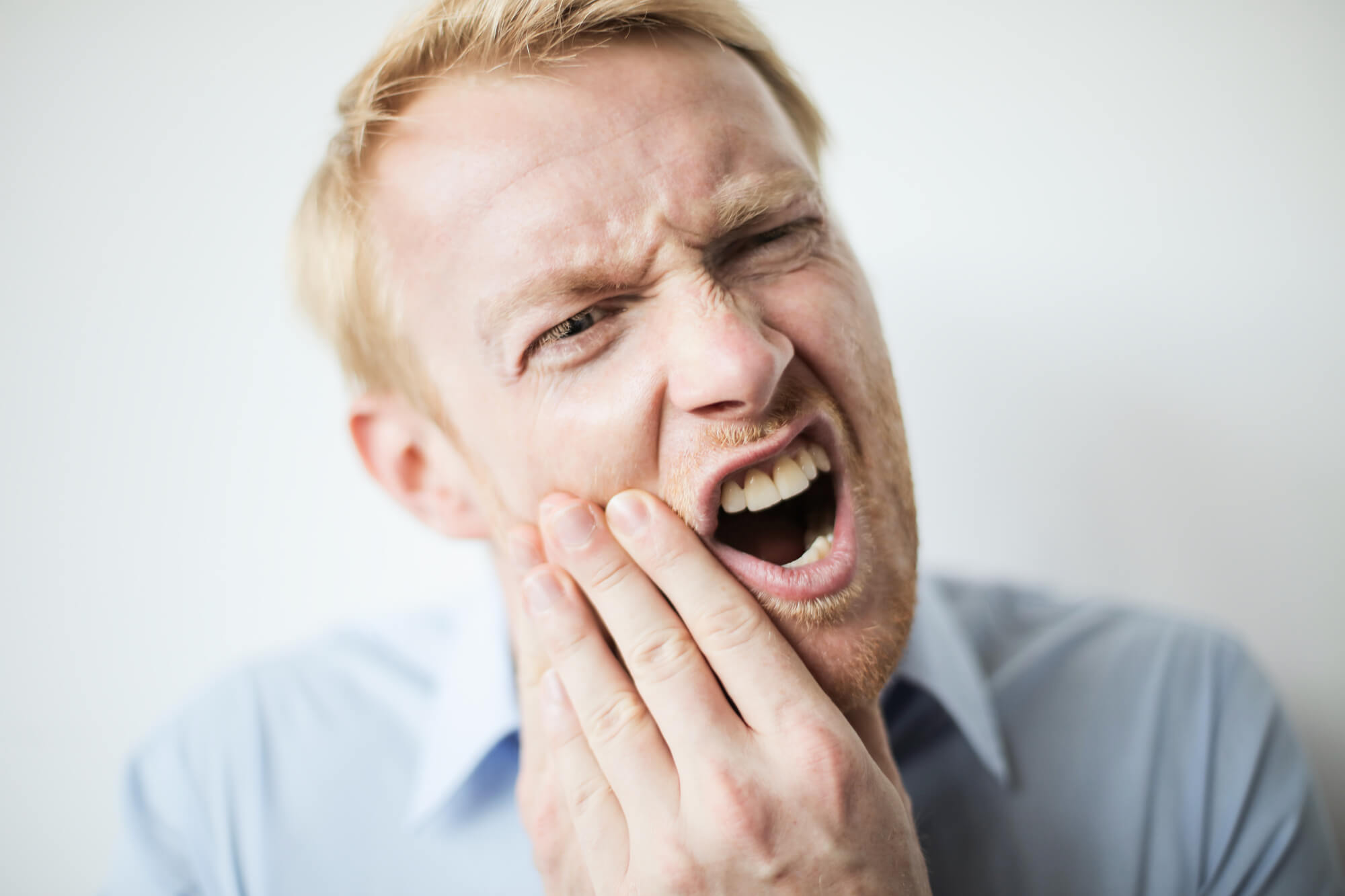 male patient enduring a toothache due to impacted wisdom teeth in Simpsonville, SC