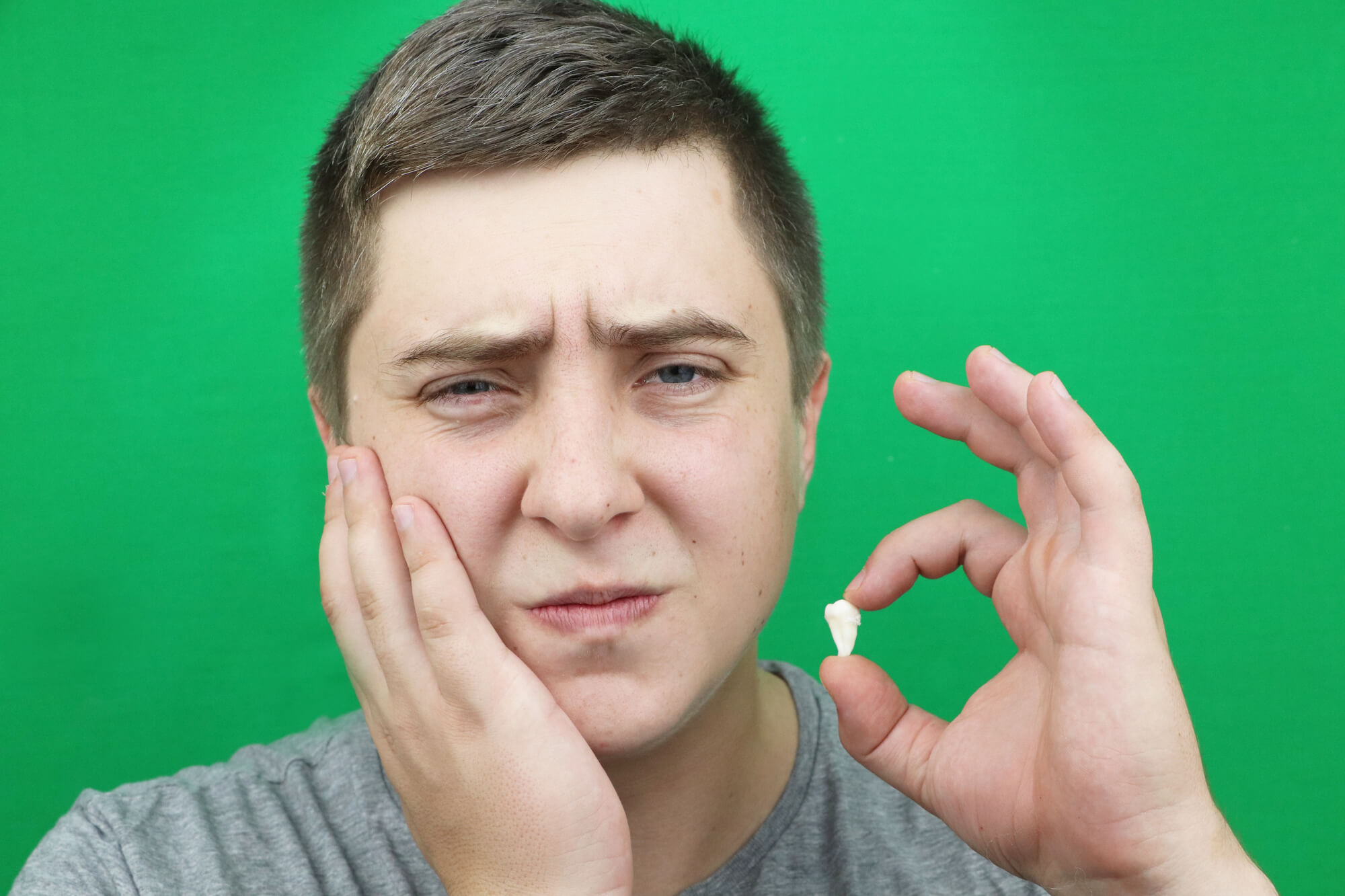 male patient holding his tooth after wisdom teeth removal in Simpsonville, SC