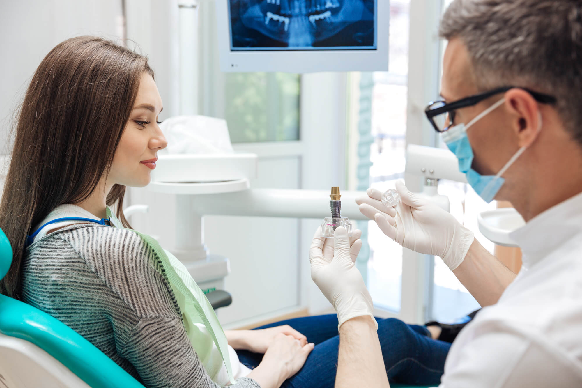 oral surgeon showing patient a sample of dental implants in Greenville SC