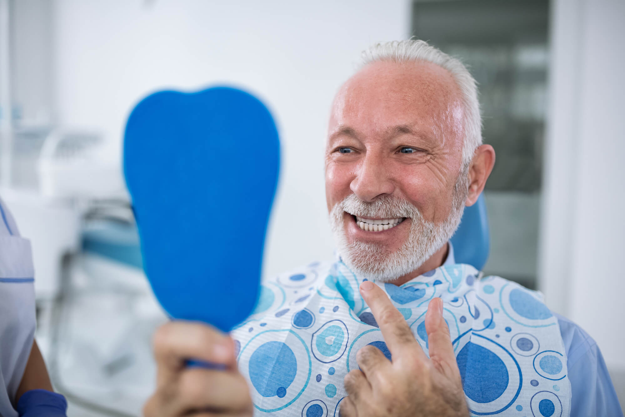 a smiling older patient looking in the mirror at the Dentist in Greenville SC